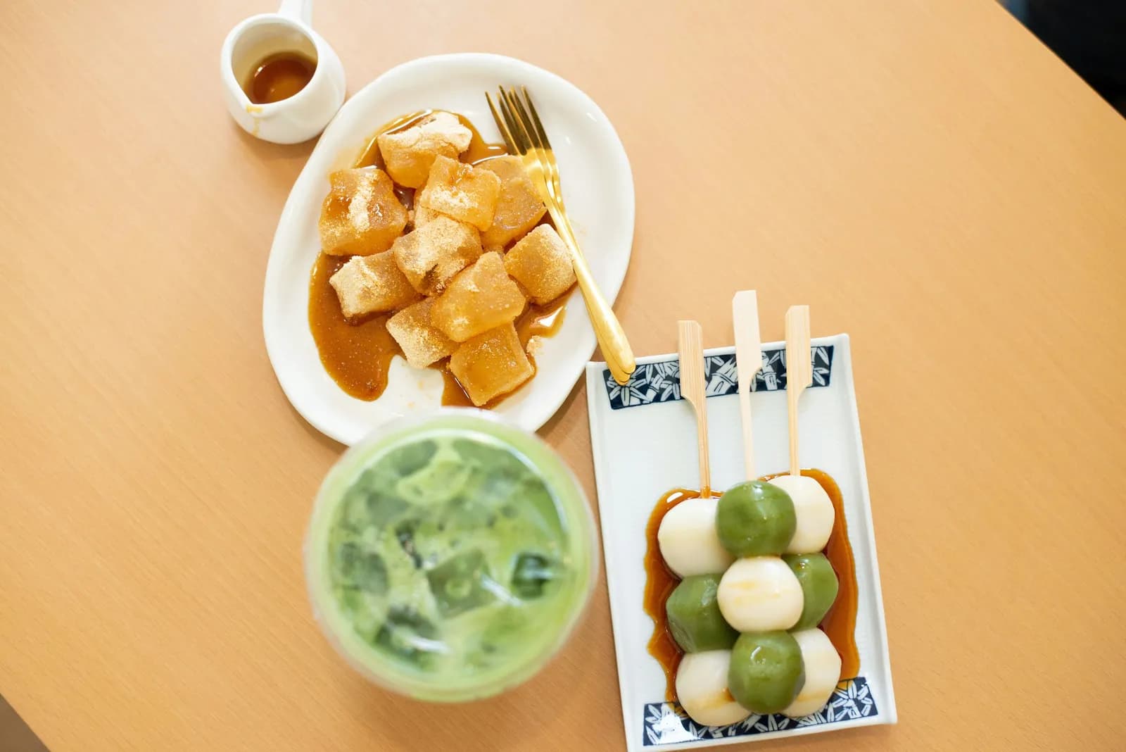 Mochis, brochettes de dango et latte glacé au matcha sur une table en bois